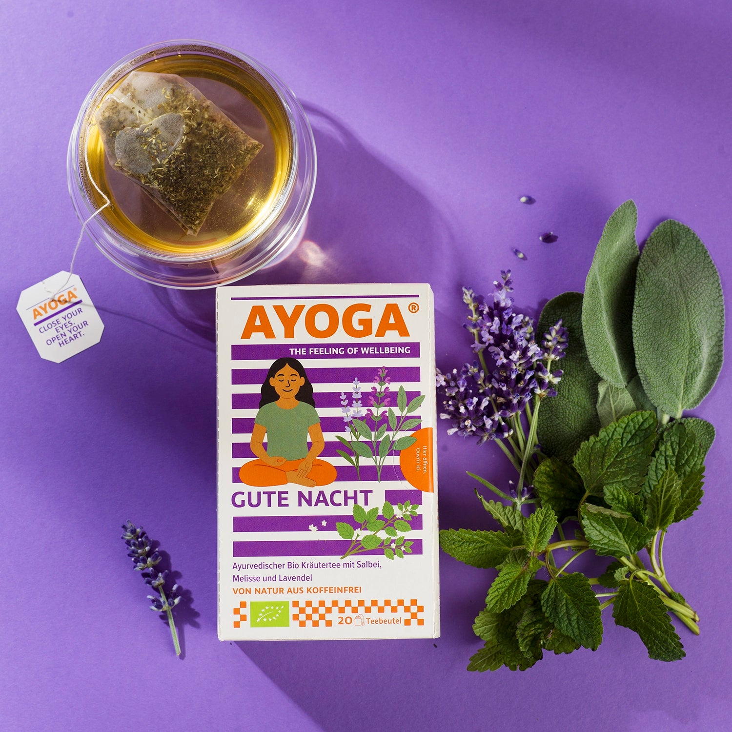 Carton de thé « Bonne nuit » sur fond violet avec verre à thé et herbes fraîches.
