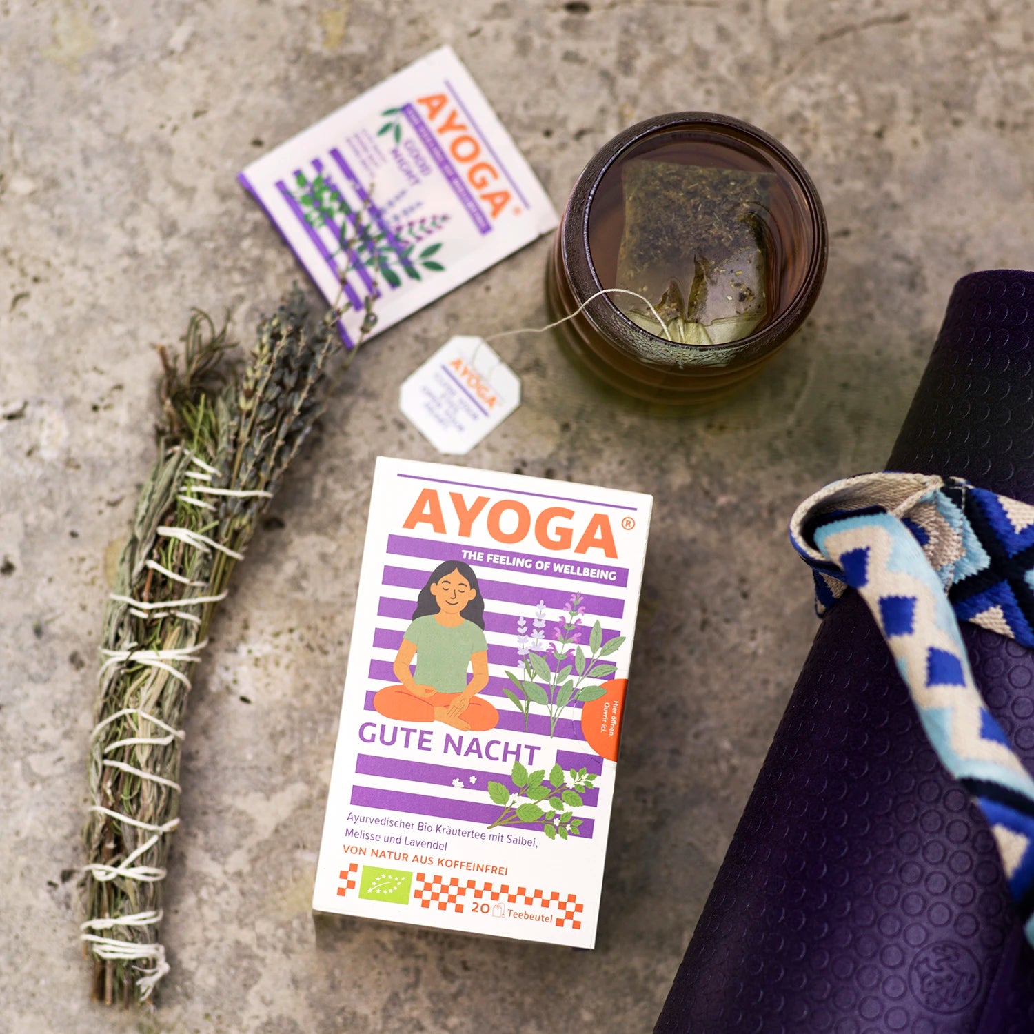 Une boîte de « AYOGA Good Night » sur un sol en pierre avec une tasse de thé.