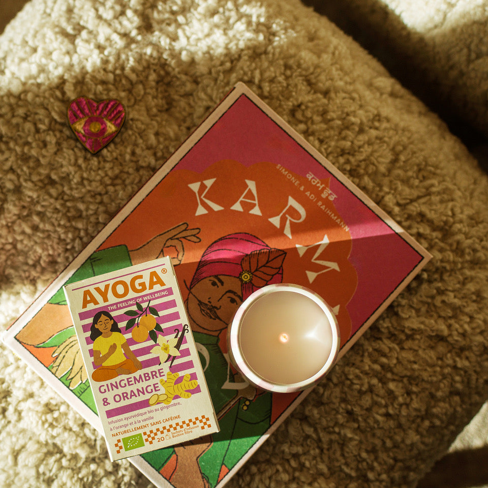 Kerze und kleine Schachtel auf Schaffell neben Herz und Buch 'Karma'.